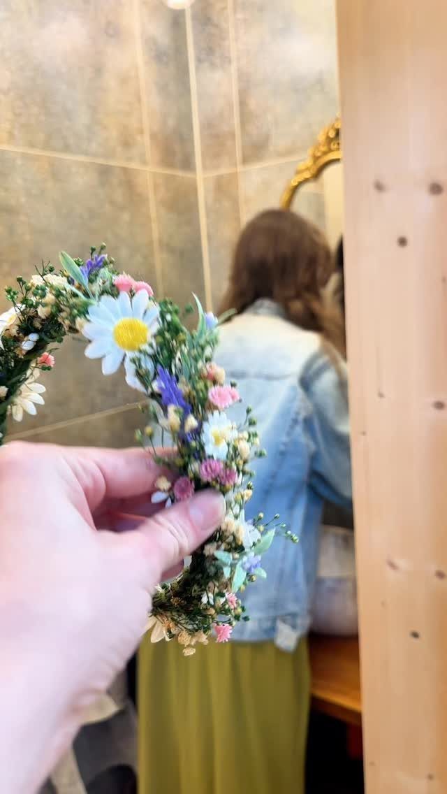 13 Wedding Ideas for Country Ceremonies That Feel Lived-In 1 A hand holding a colorful flower crown made of daisies and small wildflowers.