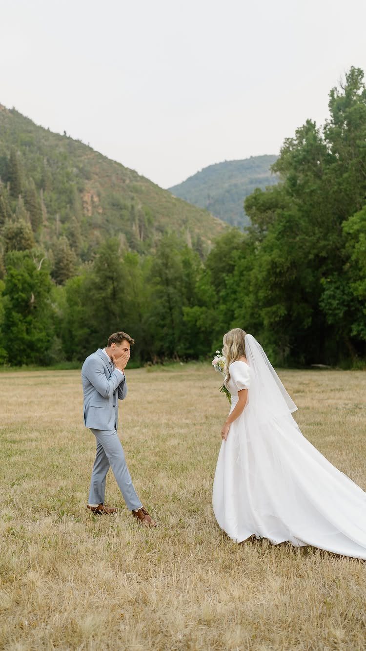 7 Wedding Picture Poses for the First Look, Sunset, and More 1 A groom reacts emotionally with his hands over his face as his bride approaches him in a field.