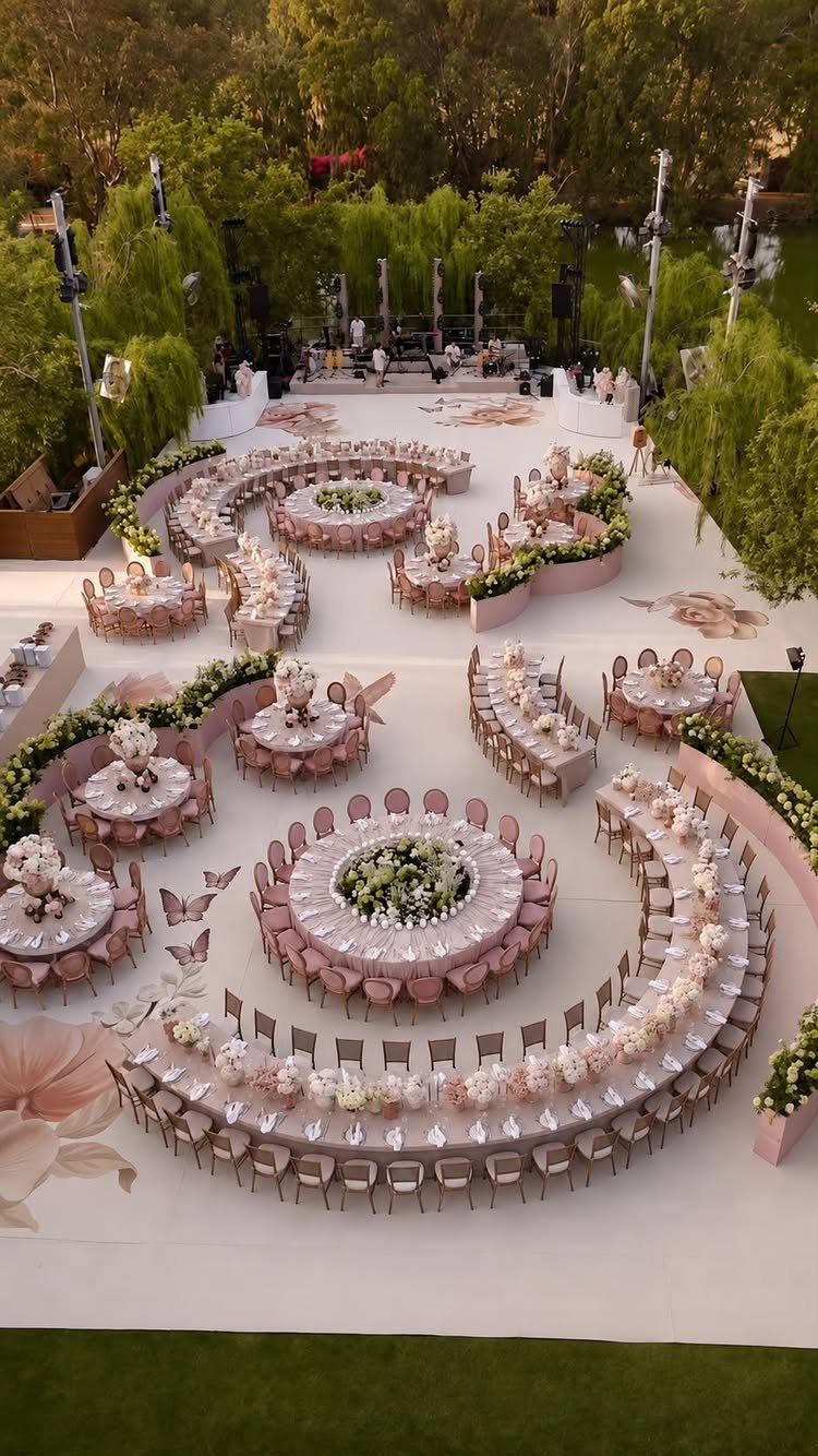16 Wedding Reception Tables and Layouts for Every Celebration 5 Circular and curved wedding reception tables with pink linens and white flowers arranged in an outdoor setting.