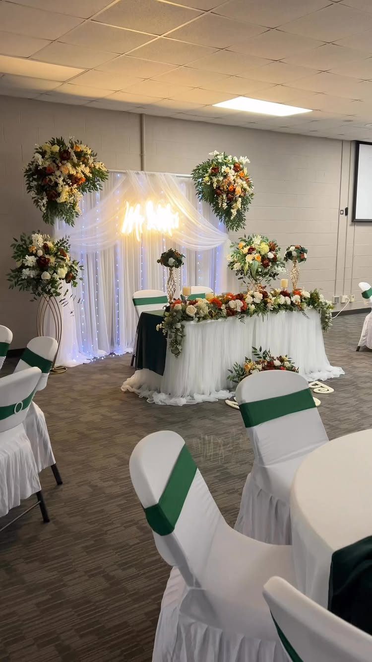 16 Wedding Reception Tables and Layouts for Every Celebration 15 A decorated wedding head table with white linens, green accents, and lush floral arrangements.