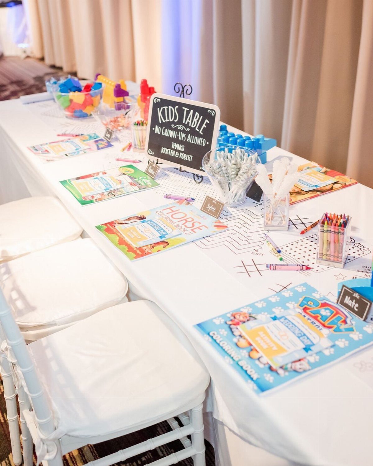 16 Wedding Reception Tables and Layouts for Every Celebration 9 A white table set with coloring books, crayons, and art supplies for a kids activity table.