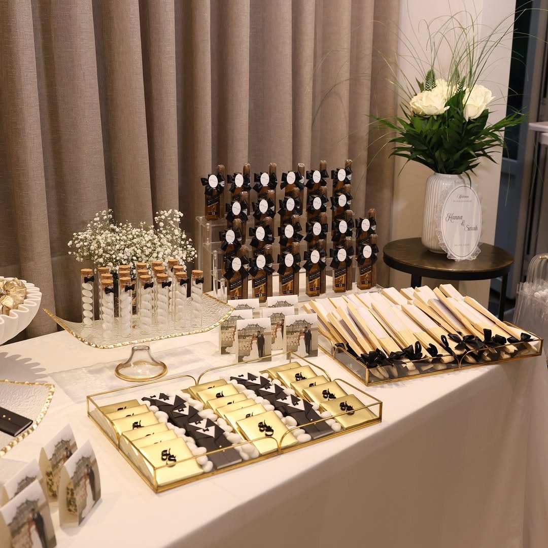 16 Wedding Reception Tables and Layouts for Every Celebration 6 Wedding favors arranged on gold trays on a white tablecloth with floral decor.