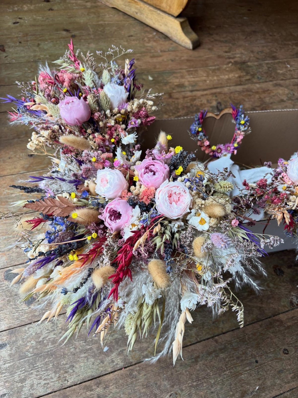 Wildflower Wedding Theme: 13 Ideas for a Light, Natural Day 12 Dried wildflower arrangements with pink roses and lavender resting on a rustic wooden floor.