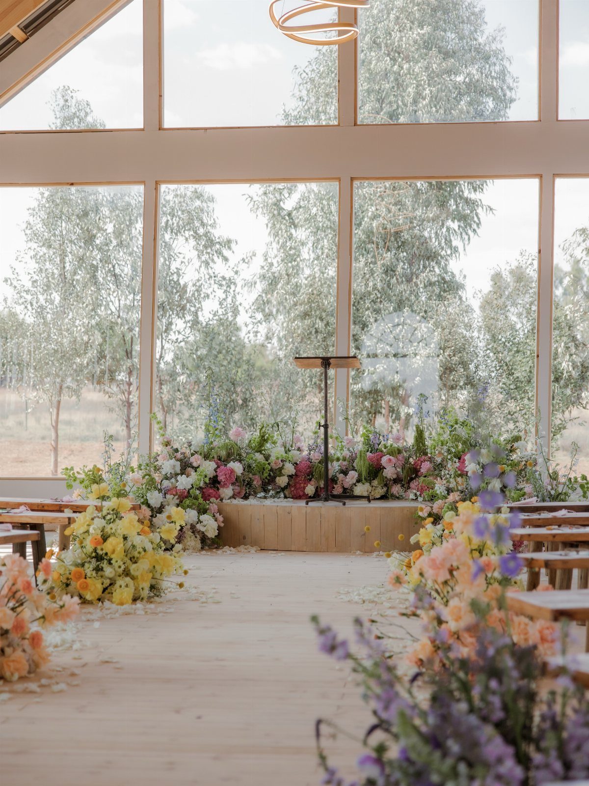 Wildflower Wedding Theme: 13 Ideas for a Light, Natural Day 11 Wildflowers arranged on a light wood floor inside a bright wedding venue with large windows.