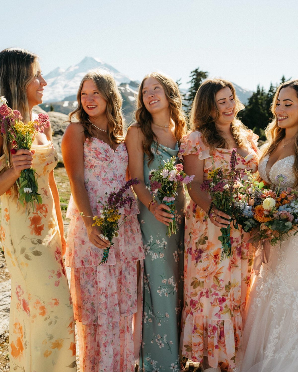 Wildflower Wedding Theme: 13 Ideas for a Light, Natural Day 7 Five women in floral dresses holding wildflower bouquets against a mountain backdrop.